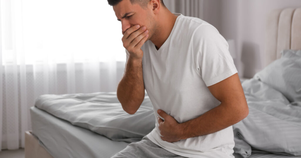 Man suffering from nausea on bed at home