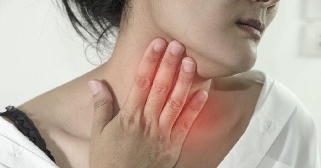 Closeup view of a young woman with Sore throat or pain on neck or thyroid gland. isolated on white background. People body problem concept